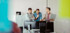 Werknemers die samen naar een computerscherm kijken op kantoor.